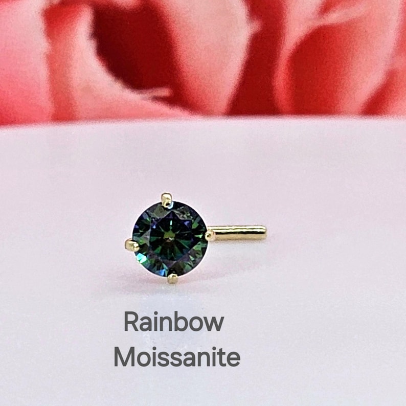 K&ouml;nnte beinhalten: Ein goldener Nasenring mit einem runden, gr&uuml;nen und blauen Moissanit-Stein. Der Stein hat einen Regenbogeneffekt. Der Text "Rainbow Moissanite" befindet sich unter dem Ring.