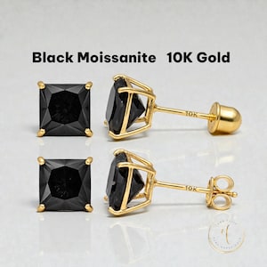 May include: Square-cut black moissanite stud earrings set in 10K gold. The earrings have a four-prong setting and a post back. The text "Black Moissanite 10K Gold" is displayed above the earrings.