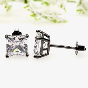 May include: A pair of black square stud earrings with clear cubic zirconia stones.