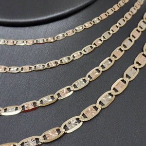 May include: Five gold chains with a diamond-shaped pattern on each link. The chains are layered on top of each other and are made of different shades of gold, including yellow, white, and rose gold.