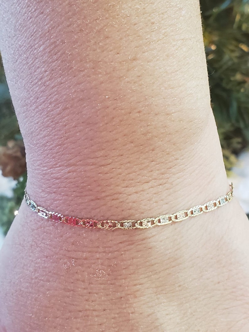 Puede incluir: Un brazalete de cadena de oro con un dise&ntilde;o delicado y estampado. El brazalete est&aacute; hecho de tres tonos diferentes de oro, creando un look &uacute;nico y elegante.