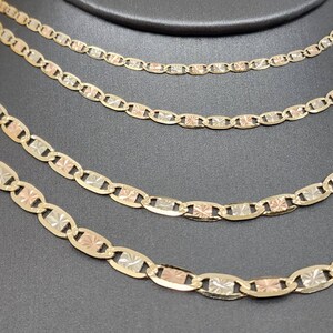 May include: Four gold chains of different lengths, each with a mariner link design. The chains are made of three-tone gold, with yellow, white, and rose gold links.
