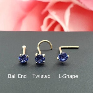 May include: Three nose rings with a blue gemstone. The rings are shown on a black surface. The rings are labeled "Ball End", "Twisted", and "L-Shape".