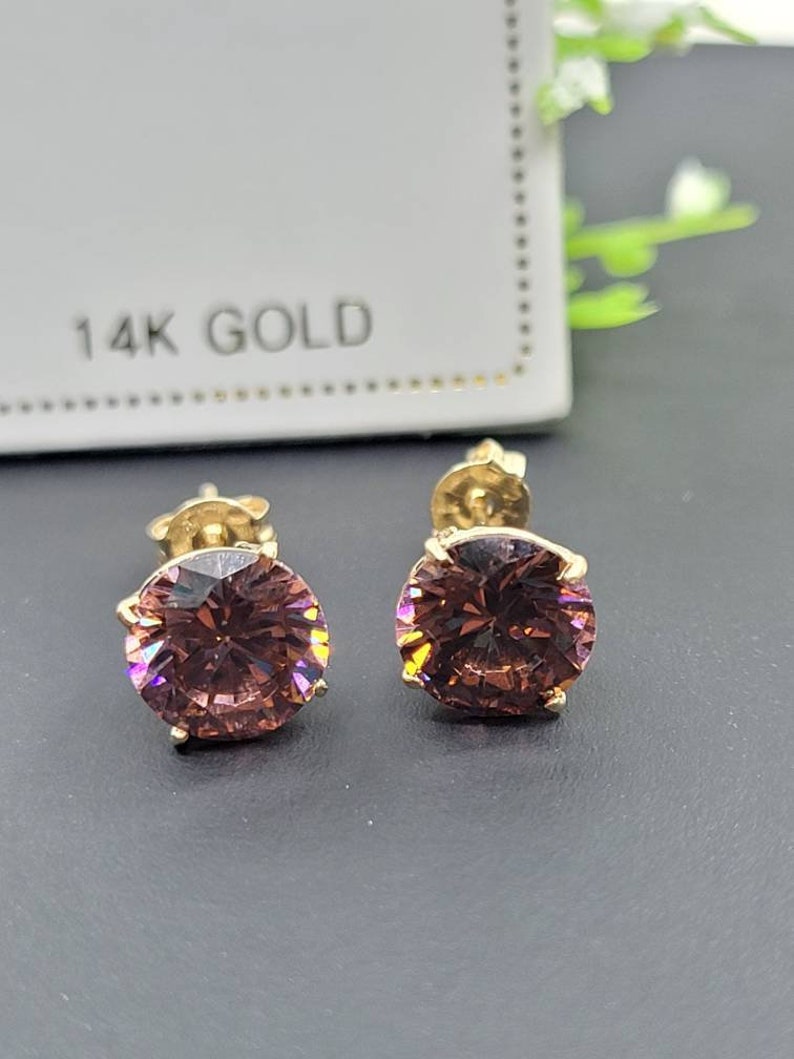 Peut inclure: Une paire de boucles d'oreilles en or 14 carats avec des pierres pr&eacute;cieuses rondes et iris&eacute;es de couleur violette.