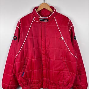May include: Red quilted jacket with white piping and a black "Type R" logo on the collar. The jacket has a zipper closure and a ribbed waistband.
