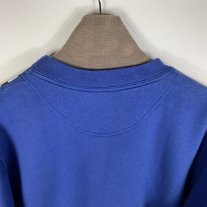 Puede incluir: Una sudadera azul con cuello redondo y una percha marr&oacute;n.