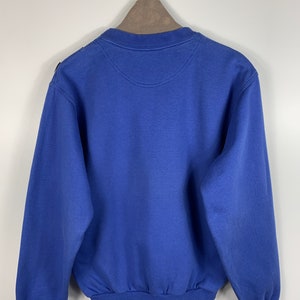 Puede incluir: Una sudadera azul con cuello redondo y mangas largas.