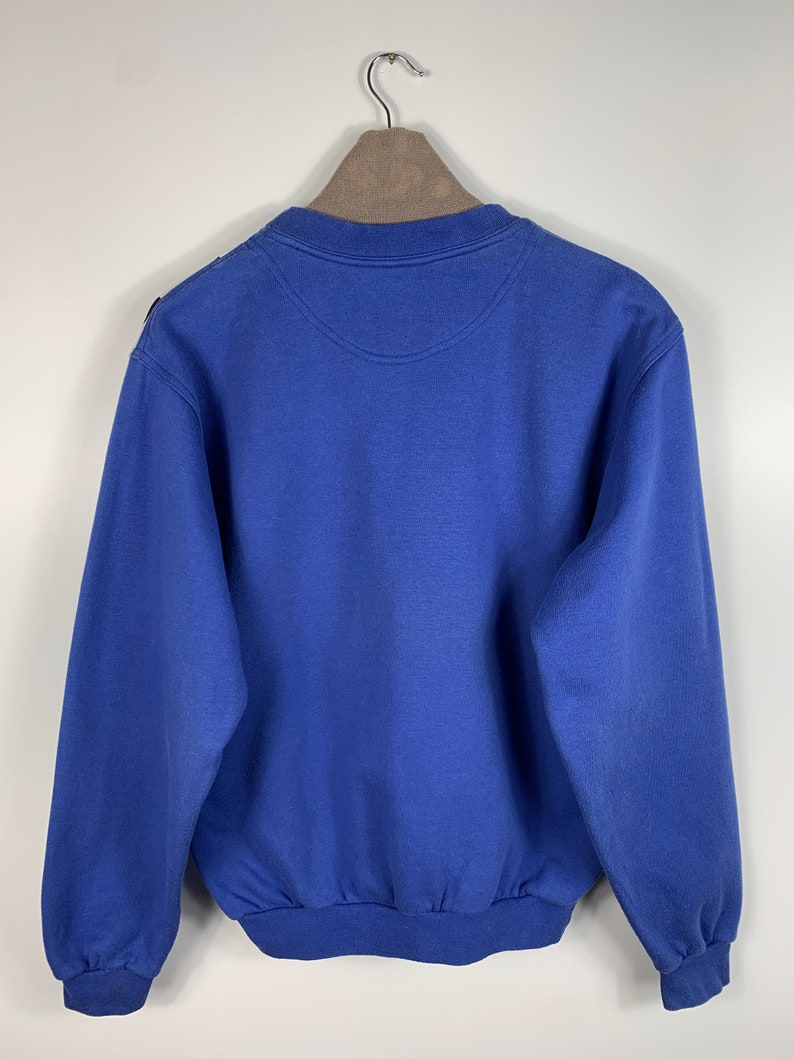 Puede incluir: Una sudadera azul con cuello redondo y mangas largas.