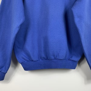 Puede incluir: Una sudadera azul s&oacute;lida con mangas largas y un dobladillo de canal&eacute;.