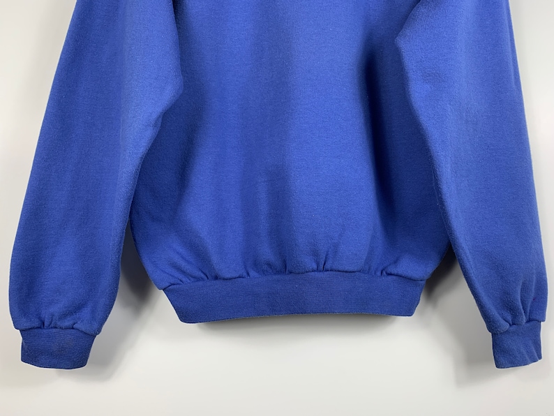 Puede incluir: Una sudadera azul s&oacute;lida con mangas largas y un dobladillo de canal&eacute;.