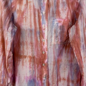 Pode incluir: Camisa de bot&atilde;o de manga comprida com um padr&atilde;o semelhante a aquarela em tons de rosa, roxo e castanho. A camisa tem um bolso no peito e o tecido parece leve e semi-transparente.