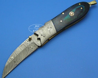 May include: A folding pocket knife with a Damascus steel blade and a blue and green wood handle. The handle has a gold accent and a small red jewel.