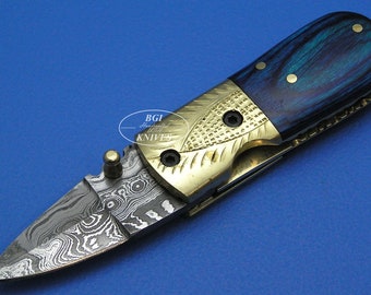 May include: A small, folding pocket knife with a blue and black wood handle and a patterned steel blade. The handle has a brass inlay with a decorative design.