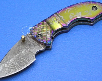 May include: A rainbow-colored folding pocket knife with a patterned handle and a Damascus steel blade.