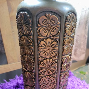 May include: A dark green lamp base with a hexagonal shape and intricate gold floral carvings. The base has a smooth, polished finish.