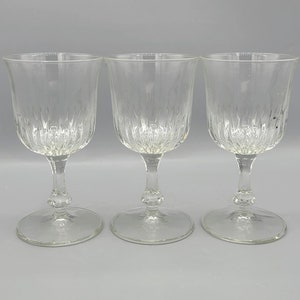 May include: Three clear glass wine glasses with a textured, diamond-shaped pattern.