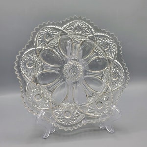May include: A clear glass serving dish with a scalloped edge and a cut glass design. The dish has six individual compartments.