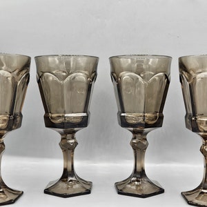 May include: Set of four brown glass wine glasses with a fluted design. The glasses have a clear, slightly amber hue and a hexagonal base.