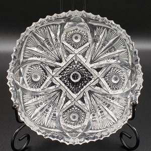 May include: A clear glass bowl with a cut glass design. The bowl has a scalloped edge and a starburst pattern in the center.