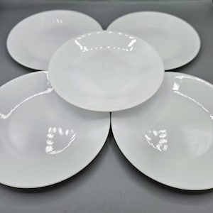 Puede incluir: Cinco platos de cena de cerámica blanca apilados en forma de flor.