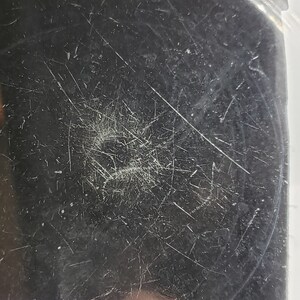 May include: Close-up of a silver metal surface with scratches and marks.