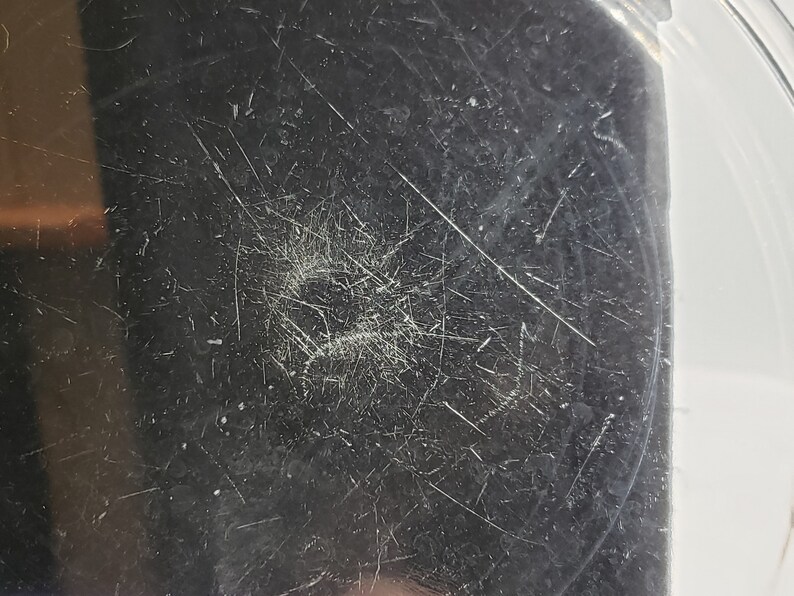 May include: Close-up of a silver metal surface with scratches and marks.