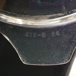 May include: Close-up of the bottom of a black pot with a silver rim. The pot has the numbers "475-C 24" printed on the bottom.