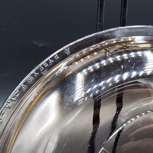 May include: Close-up of the bottom of a clear glass bowl with the words "PYREX" and "1.5 QT" etched into the glass.