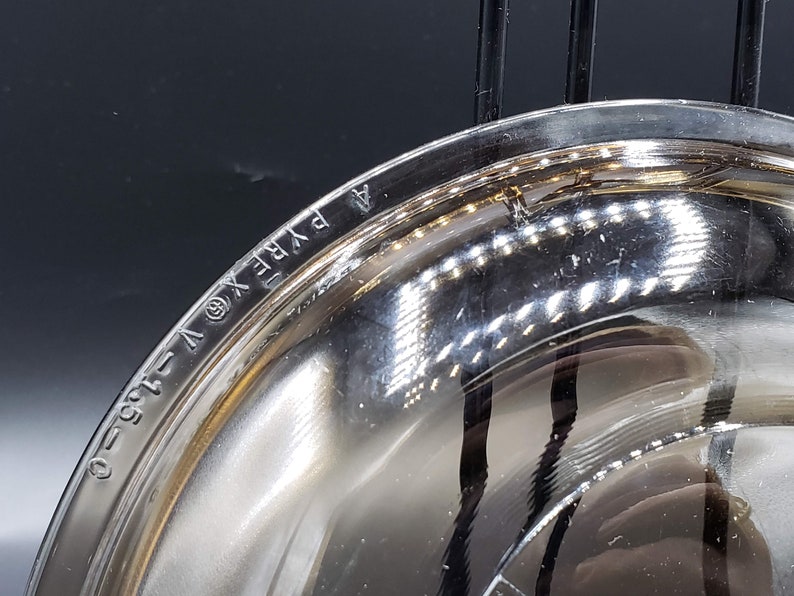 May include: Close-up of the bottom of a clear glass bowl with the words "PYREX" and "1.5 QT" etched into the glass.