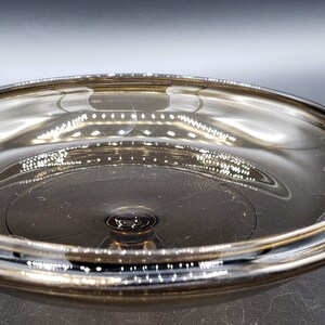 May include: A clear glass bowl with a dark brown tint. The bowl has a wide, shallow shape and a smooth, reflective surface.