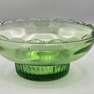 Op de afbeelding: Een groene glazen kom met een gegolfde rand en een geflute voet.