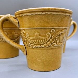 Puede incluir: Juego de cuatro tazas de cerámica marrón con un diseño floral. Las tazas tienen una base ancha y redondeada y un borde acampanado.