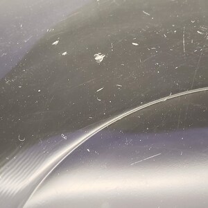 May include: Close-up of a clear plastic surface with scratches and dust particles.