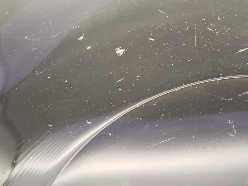 May include: Close-up of a clear plastic surface with scratches and dust particles.