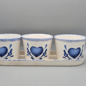 May include: Three white ceramic planters with blue heart designs and a matching white ceramic tray.