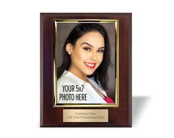 May include: A mahogany wood picture frame with a gold trim and a 5x7 inch photo insert. The photo shows a woman with dark hair and a white shirt. The frame has a gold plaque with the text "YOUR 5x7 PHOTO HERE" and "Customize Now with Your Personalized Text!"