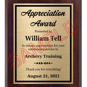 May include: A gold plaque with a black border and a mahogany frame. The plaque reads "Appreciation Award" and is presented to "William Tell" for "outstanding service to Archery Training". The date "August 21, 2021" is printed at the bottom.