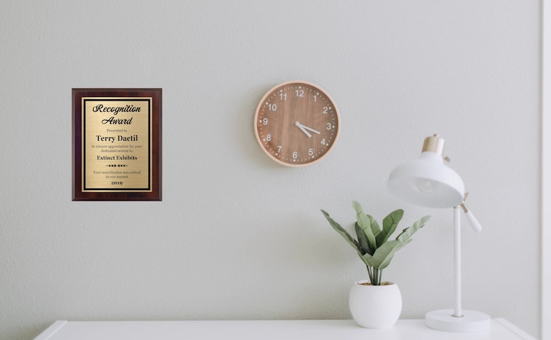 May include: A wooden plaque with a gold inscription that reads "Recognition Award" presented to Terry Dactil for dedicated service to Extinct Exhibits in 2019.