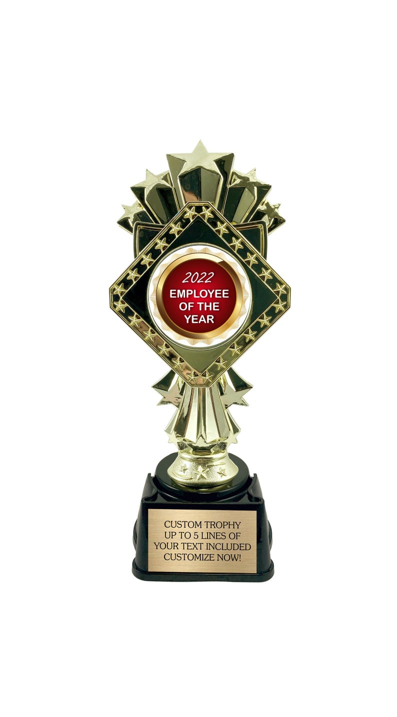 May include: Gold trophy with a red and white circular plaque that says "2022 Employee of the Year". The base of the trophy has a black plaque with the text "Custom Trophy Up to 5 lines of your text included Customize Now!"