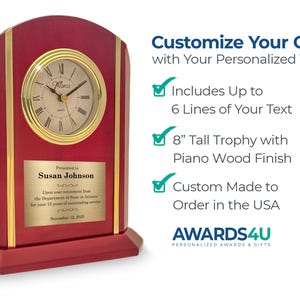 May include: A red piano wood finish clock with a gold-colored clock face and trim. The clock has a personalized plaque with text. The clock is 8 inches tall and can be customized with up to 6 lines of text.