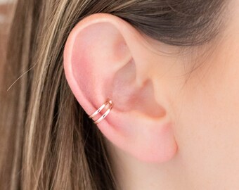 May include: A rose gold ear cuff with two thin bands. The cuff is worn on the upper part of the ear.