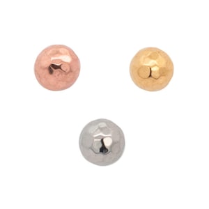 May include: Three hammered metal beads in rose gold, gold, and silver tones. Each bead is round with a textured, dimpled surface. The beads are isolated against a white background.