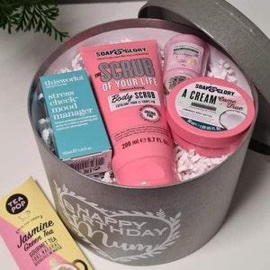 Pu&ograve; includere: Una scatola regalo argentata con una scritta bianca che dice "Buon compleanno Mamma". La scatola contiene uno scrub corpo rosa, una crema corpo rosa, un gestore dell'umore di controllo dello stress blu e una bustina di t&egrave; rosa. La bustina di t&egrave; &egrave; etichettata "T&egrave; verde al gelsomino T&egrave; gourmet 100% naturale Si scioglie in acqua".