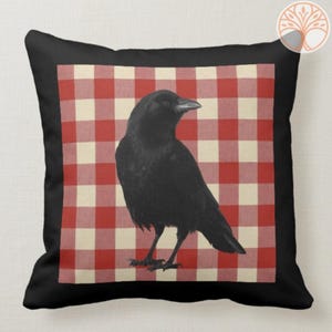 May include: Black crow with a red and white gingham background. The crow is standing on a white square in the gingham pattern.