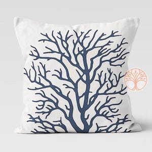 A white throw pillow with a blue silhouette of a coral branch design.