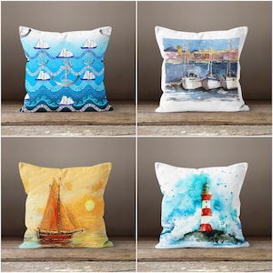 May include: Four decorative throw pillows with nautical themes. Designs include a blue wave pattern with anchors and boats, a harbor scene with sailboats, a sailboat at sunset, and a lighthouse on a rocky shore.