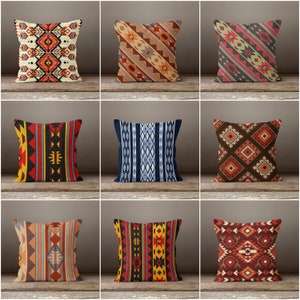May include: Nine different throw pillow designs with geometric patterns in shades of red, orange, yellow, blue, black, and white. The pillows are arranged in a grid on a wooden surface.