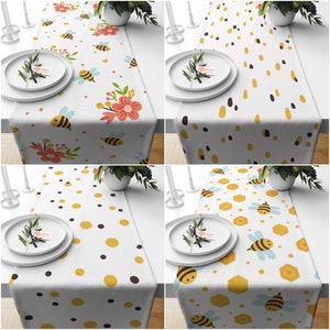 May include: Four different table runners with a bee theme. The runners feature various patterns including polka dots, honeycomb, and bees with flowers. The runners are all white with yellow and black accents.