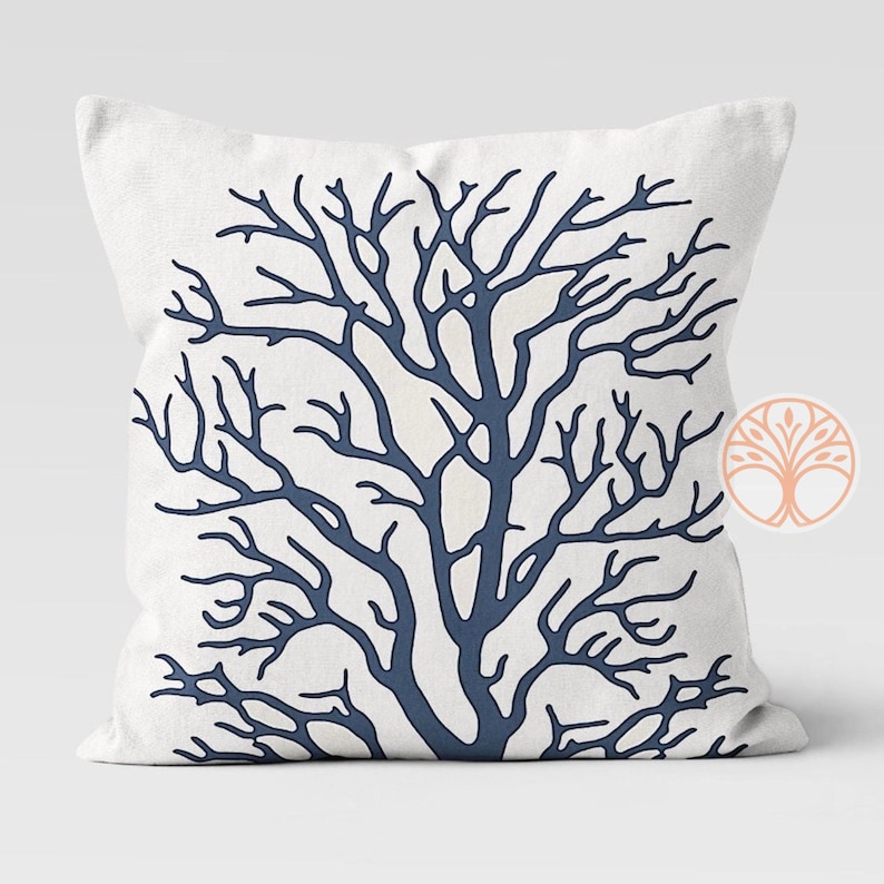 A white throw pillow with a blue silhouette of a coral branch design.