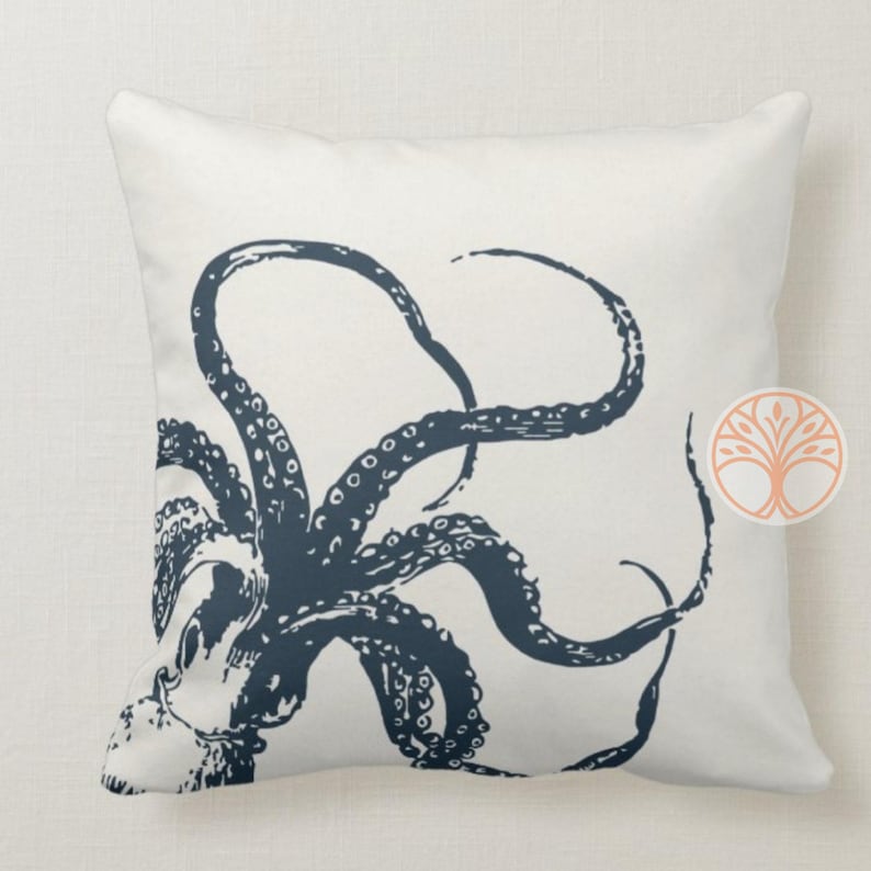 A white throw pillow with a navy blue octopus illustration. The octopus has eight tentacles and is in a curled position.
